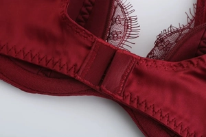 Detailed macro view of the burgundy satin bra featuring lace trim and secure back closure