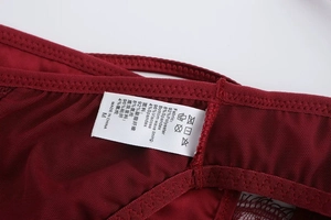 Close-up of wine red lace panties showing fabric care label and mesh texture