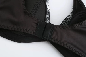 Macro detail of black eyelash lace trim and satin fabric on the sexy lingerie set back