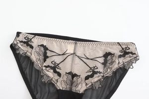 Détail de la broderie florale noire sur tulle transparent avec doublure de couleur chair