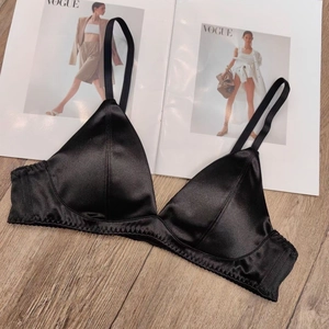 Detailed view of black satin triangle cup wireless bra on a wooden background with magazines
