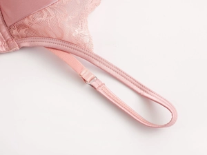 Dettaglio reggiseno in pizzo e raso rosa con cuciture fini e spallina regolabile in metallo