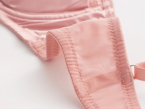 Dettaglio macro di pizzo rosa traspirante e cuciture in raso su reggiseno francese