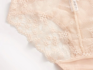 Detalle de encaje floral fino y tela de malla en lencería para mujer color carne o nude