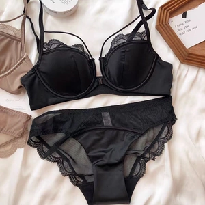 Flat lay of elegant black silk lingerie set with delicate eyelash lace details on white silk