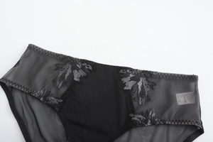 Détail de culotte en résille noire avec broderie florale délicate et taille élastique