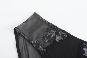 Détail du tissu en maille noire avec broderie florale délicate et coutures plates