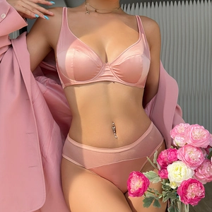 Detailed view of a pink satin lingerie set featuring a wired bra and mesh patchwork panties