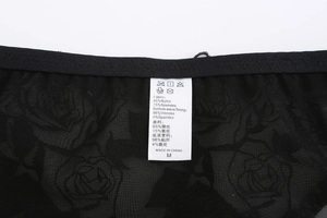 Detalle de la etiqueta en sujetador de encaje rosa negra con info de materiales y talla M