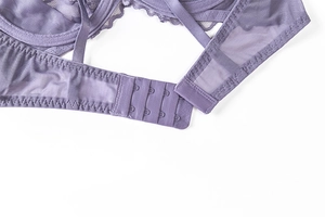 Close-up of purple lace bra back closure featuring three-row hook-and-eye and mesh fabric