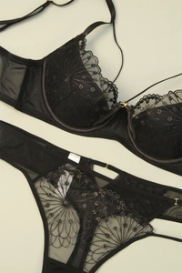 Flat lay of black floral embroidery lace bra set with sheer mesh and metal hardware