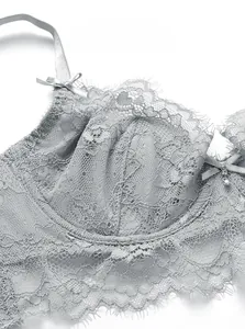 Close-up of gray floral lace bra featuring eyelash edges, a small bow, and a shiny pendant
