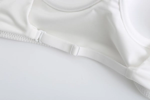 Detail of adjustable white shoulder strap with plastic buckle on a seamless bra
