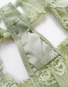 Close-up of sage green floral lace and stitching details on a mesh thong