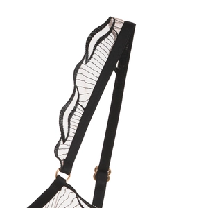 Detailed macro view of black lace embroidery shoulder strap with gold metal ring link