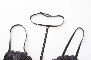 Detail of black mesh lace bra with purple glitter embroidery and rhinestone neck strap