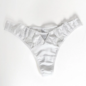 Makroansicht der weißen floralen Stickerei-Spitze und Satin-Stoff am Slip für Damen