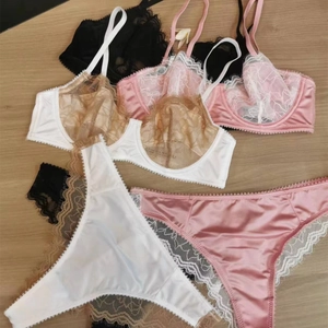 Ensembles de lingerie en dentelle rose, blanc et noir sur fond de bois clair
