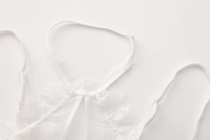 Close-up of intricate floral eyelash lace and adjustable thin straps on a white bra