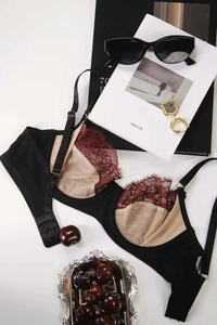 Detail of black and burgundy lace bra with adjustable straps and back buckle design