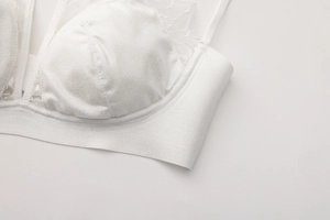 Detail of white lace bra featuring shimmering silver fabric and delicate floral edges