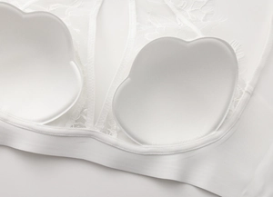 Detailed macro view of white lace bra interior featuring soft cup pads and eyelash edges