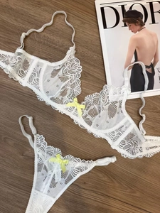 Detailed view of white floral lace lingerie set with silk bows on wooden background