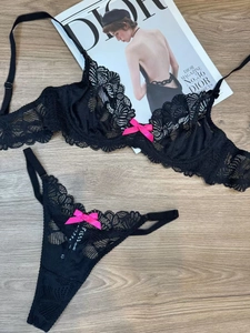 Detail of black lace lingerie set featuring sheer floral embroidery and pink satin bows