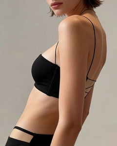 Detail of black seamless bra with thin cross straps and matching cutout waist panties
