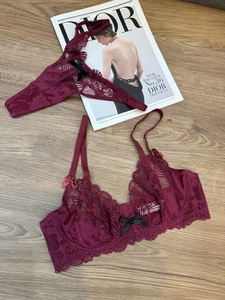 Flat lay of wine red lace lingerie set with black bows on a natural wooden background