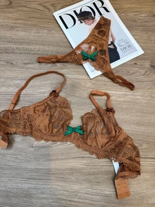 Detail view of brown floral lace lingerie set with satin green bows on wooden floor