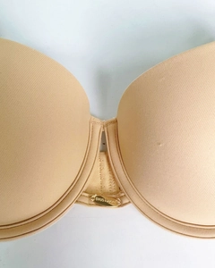 Dettaglio ravvicinato di reggiseno push-up color carne senza cuciture con logo dorato
