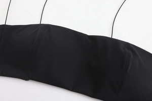 Detailed close-up of seamless black fabric with thin straps and refined stitching texture