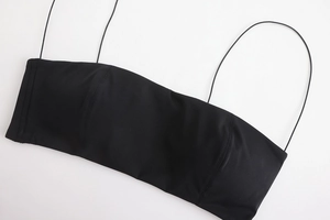 Detail of a minimalist black bralette featuring thin straps and vertical seam construction
