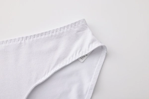 Detailed macro view of white cotton panties with spandex fabric texture and washing label