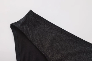 Detailed close-up of sexy black low waist panties with shiny glitter fabric and cotton lining