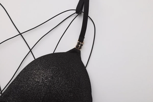 Detail of black glitter bra cup with gold and crystal luxury shoulder strap link