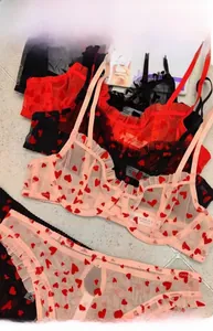 Flat lay of sheer mesh lingerie sets with red heart prints in black, red, and pink colors