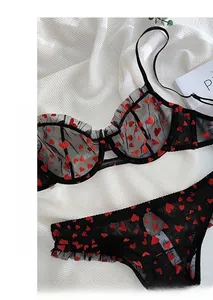 Detail view of black mesh lingerie set with red heart print and delicate pleated edges