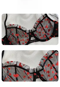Detail showing sheer black mesh bra with red heart patterns and delicate lace edges