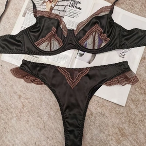 Flat lay of black satin and brown lace lingerie set on a fashion magazine