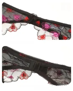 Detail von schwarzer Netzspitze mit rosa Herzstickerei und gewellten Rändern