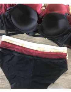 Zwarte push-up bh set met vier meerkleurige naadloze slips op donkere houten ondergrond