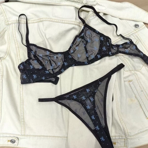Zwarte doorschijnende lingerie set met lichtblauwe strikprint en beugelbeha-ontwerp