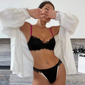 Sexy schwarzes Spitzenunterwäsche-Set mit Punkten und rosa Trägern auf Marmor