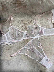 Detailed embroidery of pink flowers on white mesh lingerie set with lace accents