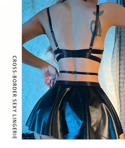 Rear view of sexy black faux leather lingerie set with pleated mini skirt on white rug