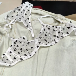 Flat lay of white mesh lingerie set with black bow print and steel underwire support