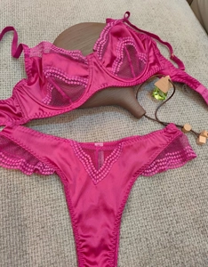 Flat lay of magenta satin and lace bra and thong set on a textured background