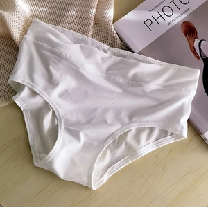 Detail of white seamless high waist underwear on wooden surface with magazine background